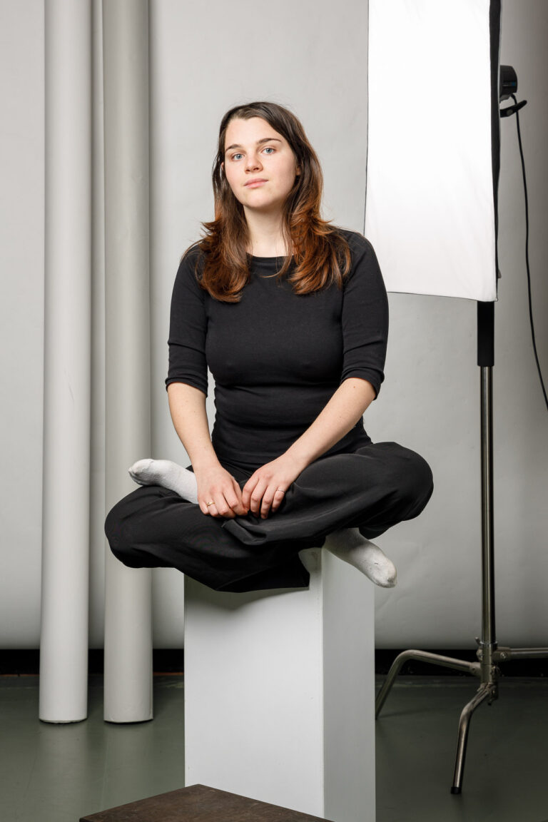 Porträt Franziska Clementi, Theatertherapeutin und Schauspielerin, im Schneidersitz auf einem Podest – ruhige, achtsame Haltung.
